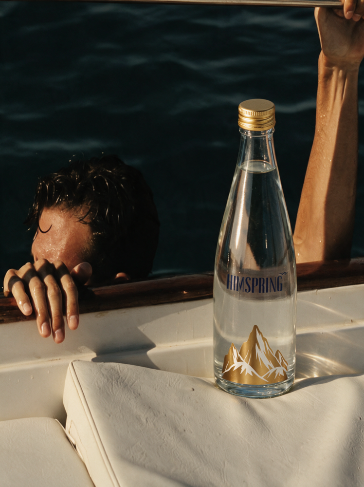 A Himspring bottle on a boat cushion, a swimmer at the gunwale beyond