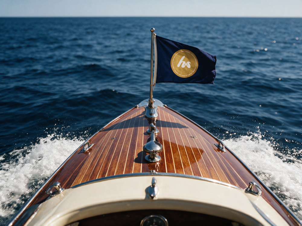 The Himspring emblem on a burgee at the bow of a classic wooden boat at sea